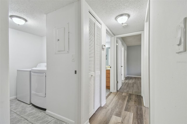 corridor with electric panel, light hardwood / wood-style flooring, and washing machine and dryer