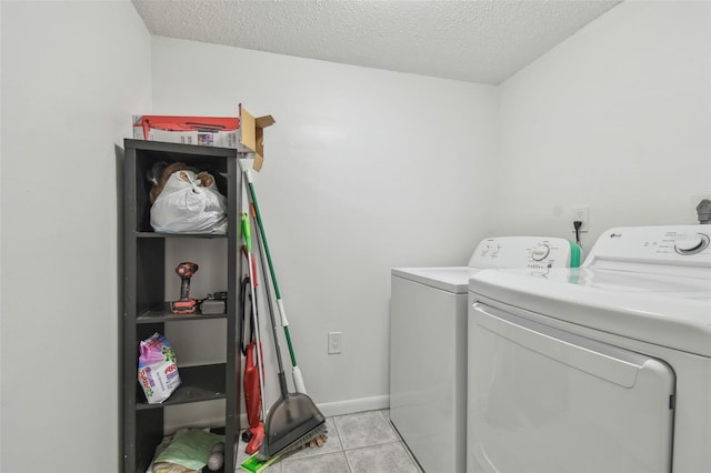 clothes washing area with independent washer and dryer, a textured ceiling, and light tile patterned flooring