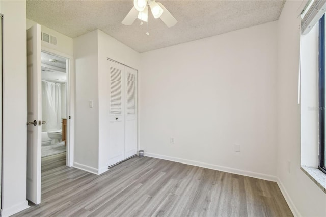 unfurnished bedroom featuring a textured ceiling, ceiling fan, light hardwood / wood-style floors, and a closet