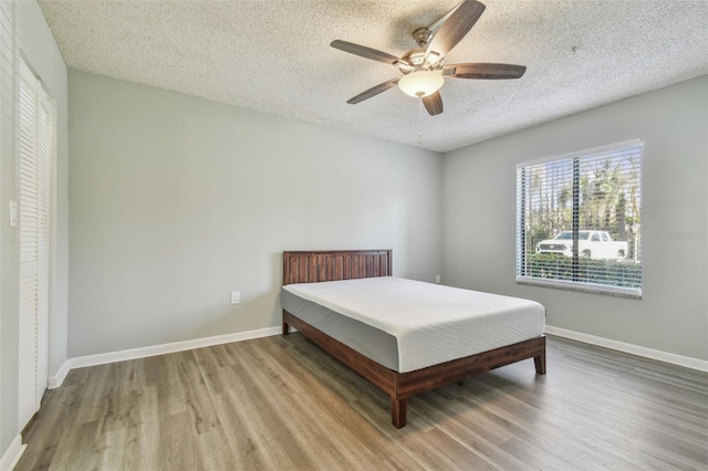 bedroom featuring light wood-type flooring, a textured ceiling, and ceiling fan