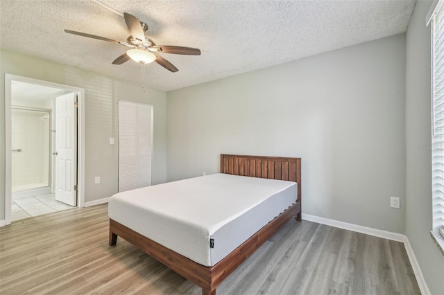 bedroom featuring a textured ceiling, ceiling fan, light hardwood / wood-style floors, and connected bathroom