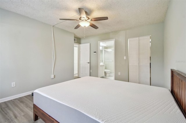 bedroom featuring a textured ceiling, ceiling fan, light hardwood / wood-style flooring, a closet, and ensuite bath