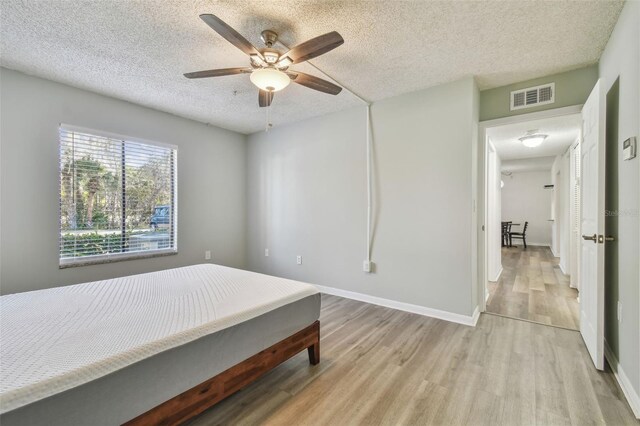 bedroom featuring ceiling fan, light wood-type flooring, and a textured ceiling