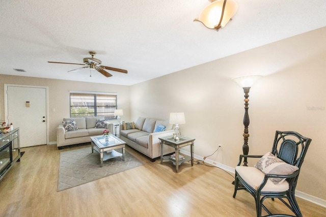 living room with ceiling fan, light hardwood / wood-style floors, and a textured ceiling