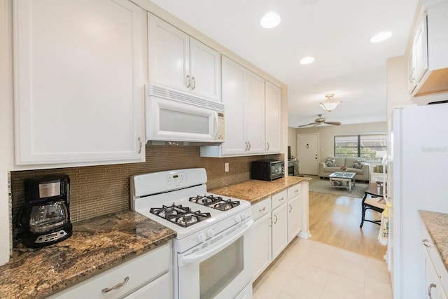 kitchen featuring white appliances, white cabinetry, ceiling fan, and dark stone counters