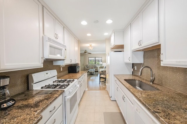 kitchen featuring white appliances, dark stone counters, sink, ceiling fan, and white cabinetry