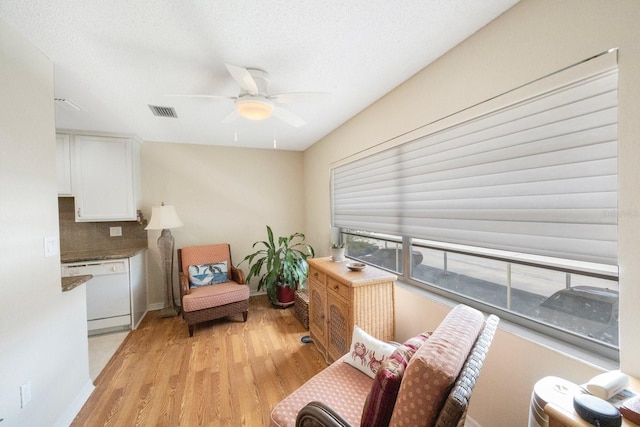 sitting room featuring a textured ceiling, light hardwood / wood-style flooring, and ceiling fan