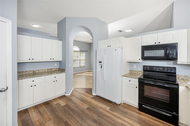 kitchen with light stone countertops, white cabinetry, dark hardwood / wood-style floors, and black appliances