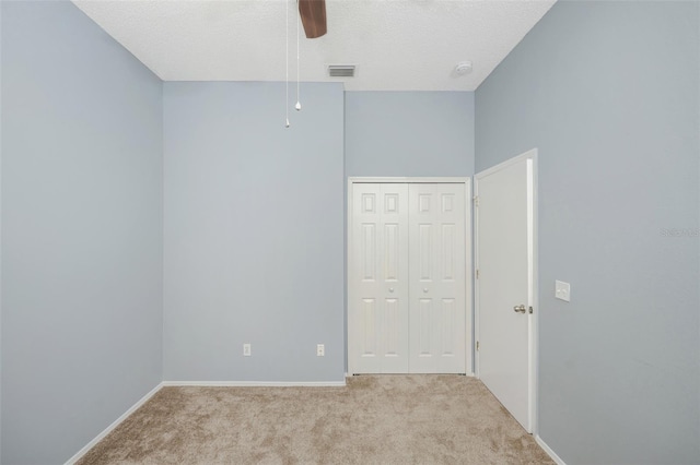 spare room with light carpet, ceiling fan, a towering ceiling, and a textured ceiling