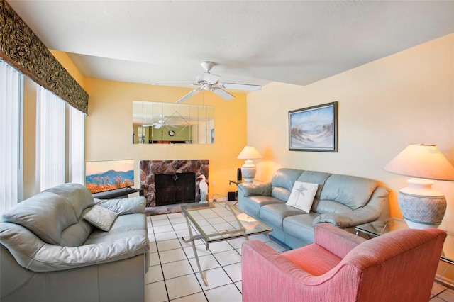 tiled living room featuring ceiling fan and a stone fireplace