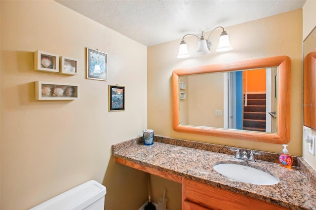 bathroom with a textured ceiling, toilet, and vanity