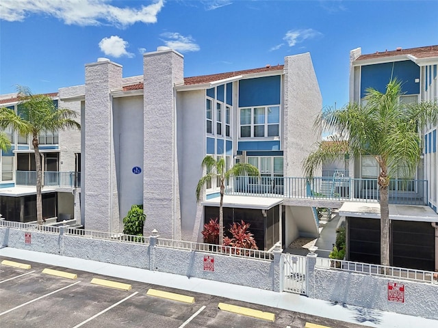 343 Rex Pl Unit F, Madeira Beach, FL 33708 - view of apartment building / complex featuring uncovered parking and a fenced front yard