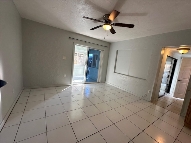 tiled empty room with ceiling fan and a textured ceiling