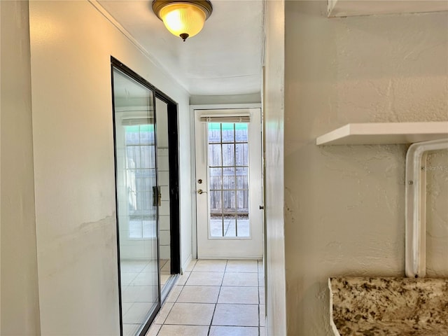 doorway with light tile patterned floors and ornamental molding