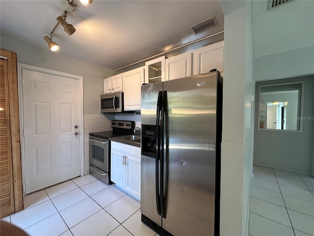 kitchen with decorative backsplash, light tile patterned flooring, stainless steel appliances, and white cabinetry