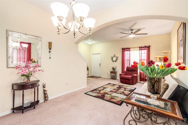 carpeted living room with ceiling fan with notable chandelier