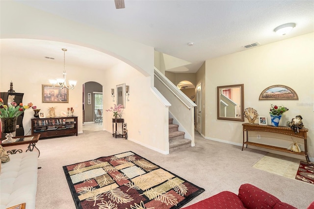 living room featuring a textured ceiling, light colored carpet, and a chandelier