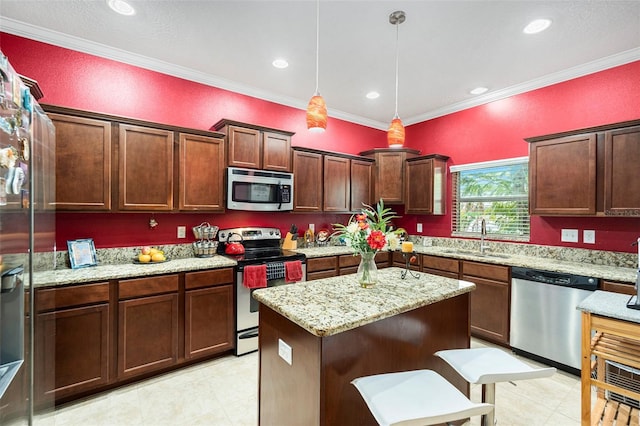 kitchen with stainless steel appliances, hanging light fixtures, light stone counters, a kitchen island, and sink