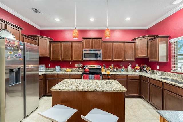 kitchen featuring sink, appliances with stainless steel finishes, pendant lighting, and a center island