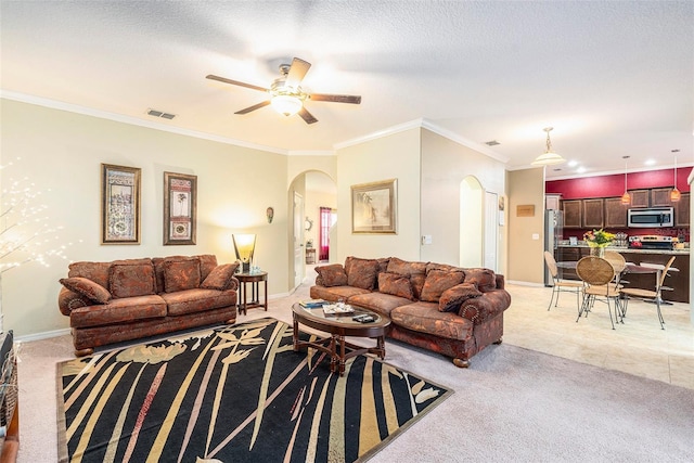 carpeted living room with ceiling fan, ornamental molding, and a textured ceiling