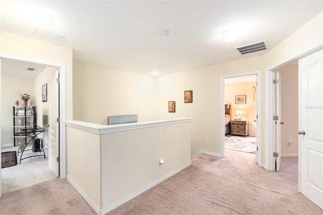 hall featuring a textured ceiling and light carpet