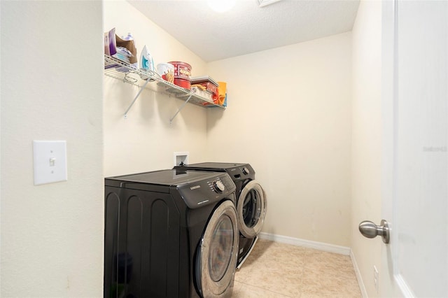 washroom featuring washer and dryer, a textured ceiling, and light tile patterned floors