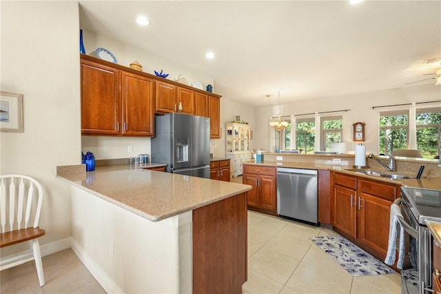 kitchen featuring light stone counters, kitchen peninsula, light tile patterned floors, appliances with stainless steel finishes, and sink