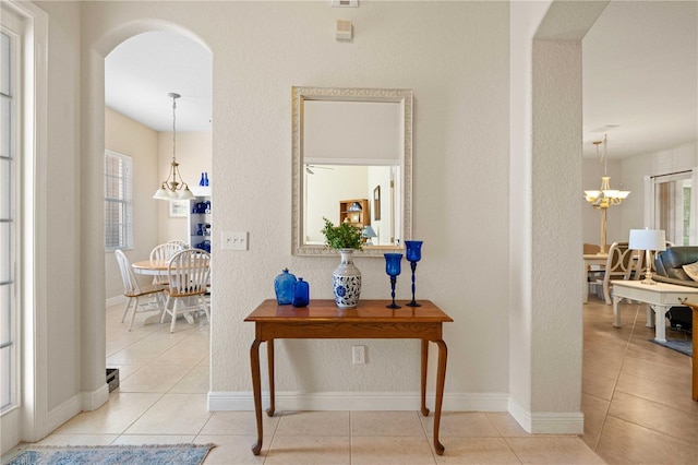 corridor featuring an inviting chandelier and light tile patterned floors