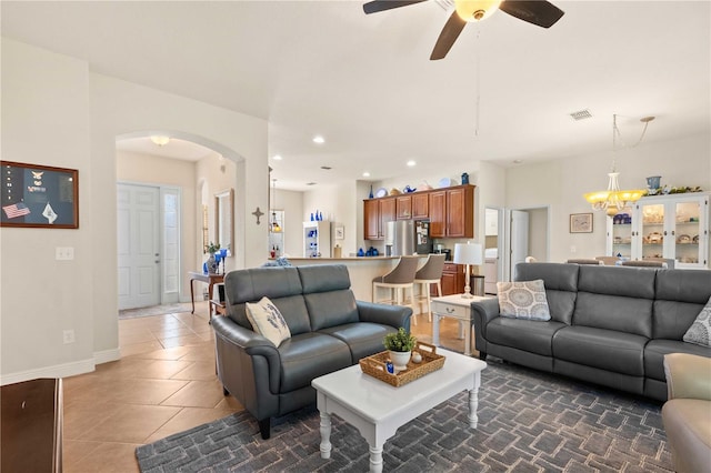 tiled living room with ceiling fan with notable chandelier