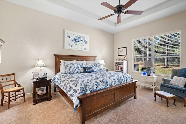 carpeted bedroom featuring a raised ceiling and ceiling fan