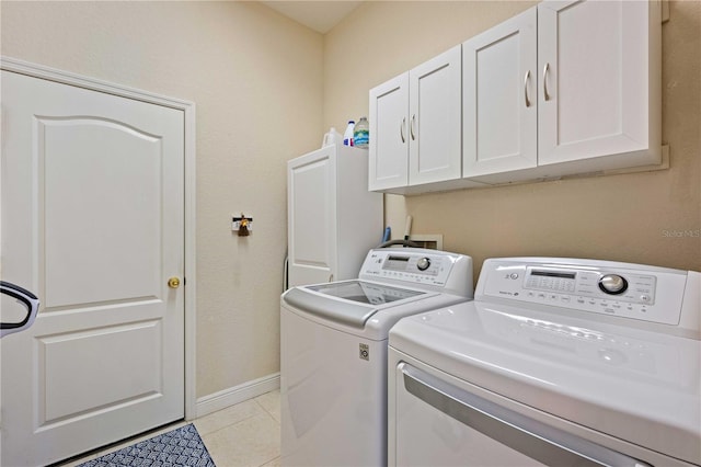 washroom with light tile patterned flooring, cabinets, and washer and dryer