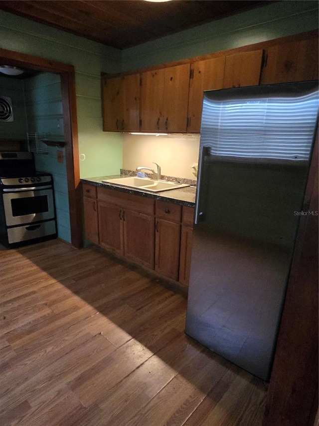 kitchen with refrigerator, stainless steel gas stove, wood-type flooring, and sink