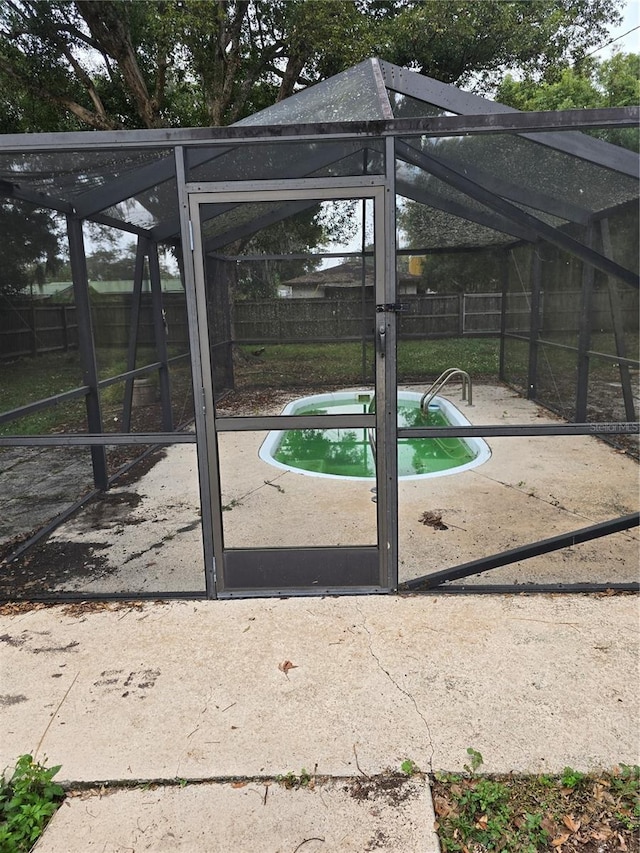 exterior space with a fenced in pool, glass enclosure, and a patio area