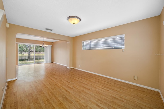 empty room with an inviting chandelier and light hardwood / wood-style floors