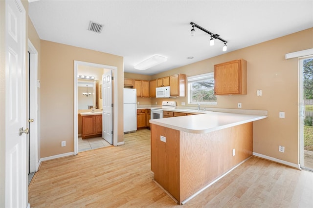 kitchen with light wood-type flooring, kitchen peninsula, sink, and white appliances