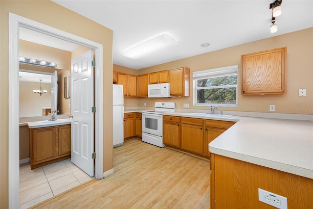 kitchen featuring light wood-type flooring, an inviting chandelier, sink, and white appliances