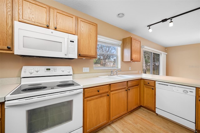 kitchen featuring white appliances, track lighting, light hardwood / wood-style floors, sink, and kitchen peninsula