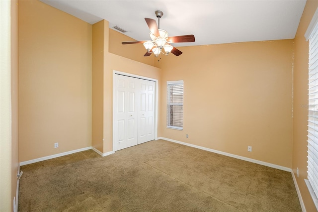 unfurnished bedroom featuring ceiling fan, a closet, carpet floors, and vaulted ceiling