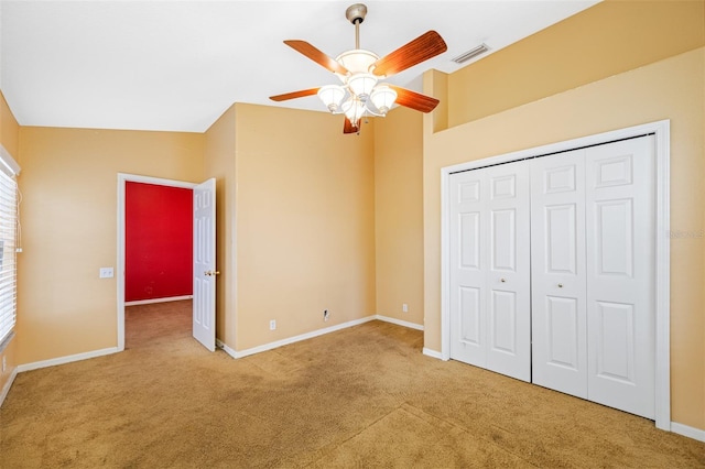 unfurnished bedroom with ceiling fan, a closet, carpet floors, and lofted ceiling