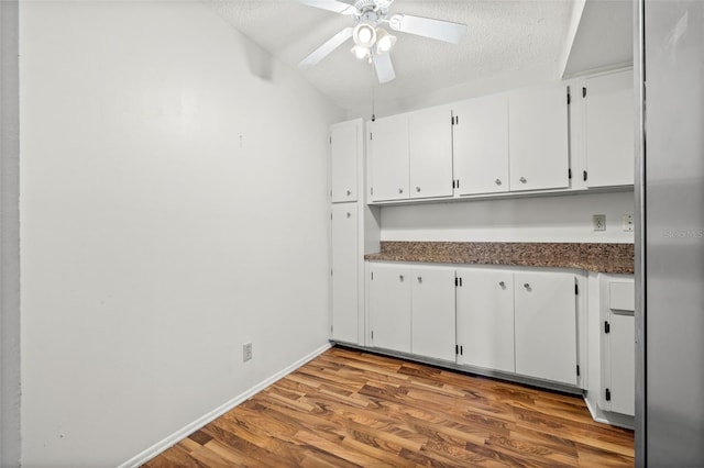 kitchen featuring a textured ceiling, hardwood / wood-style flooring, white cabinets, and ceiling fan