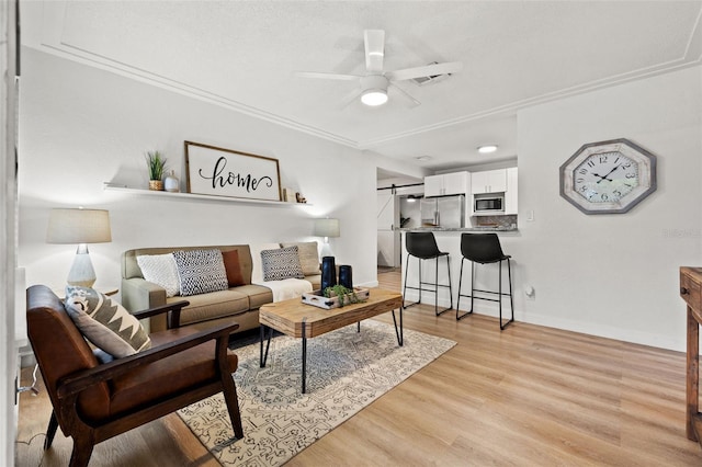 living room with light hardwood / wood-style floors, ornamental molding, and ceiling fan