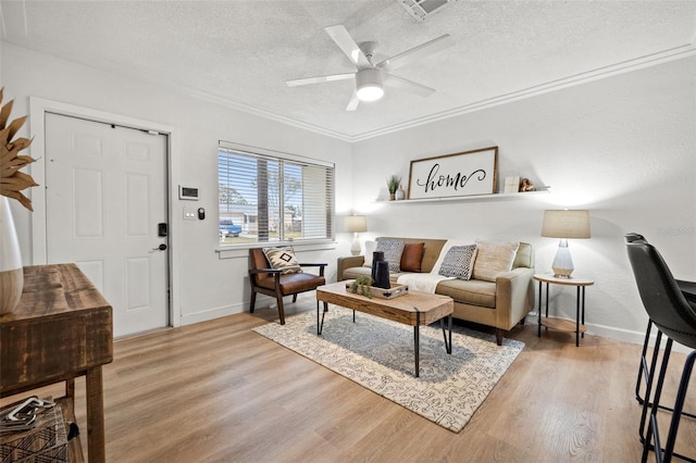 living room featuring ceiling fan, hardwood / wood-style flooring, ornamental molding, and a textured ceiling