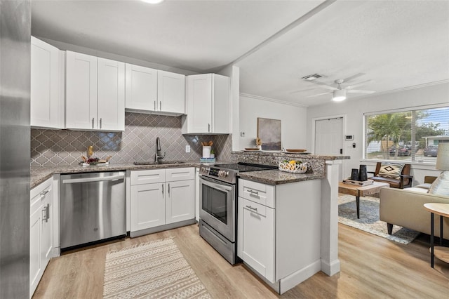 kitchen featuring kitchen peninsula, appliances with stainless steel finishes, sink, and white cabinetry