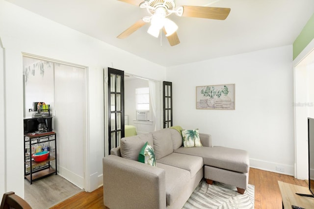 living room featuring cooling unit, light wood-type flooring, and ceiling fan