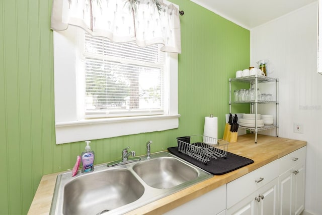 kitchen featuring sink, butcher block countertops, and white cabinetry