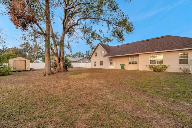 back of house with a storage shed and a yard