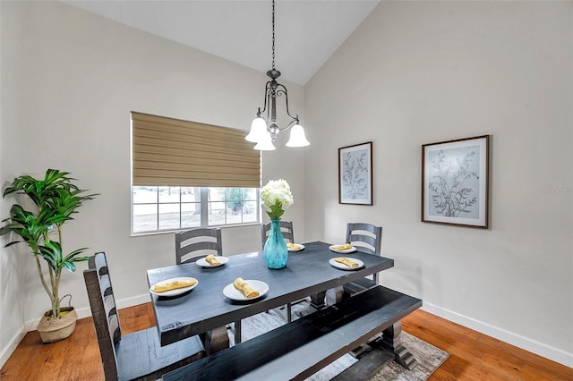 dining space featuring hardwood / wood-style floors, lofted ceiling, and a notable chandelier