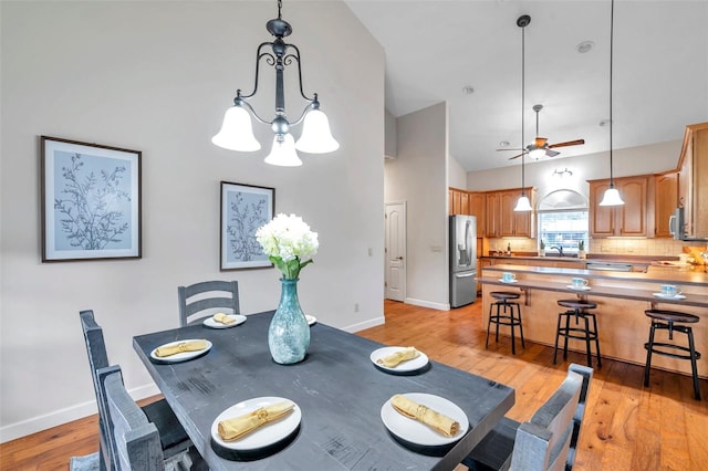 dining area with light hardwood / wood-style floors and ceiling fan with notable chandelier