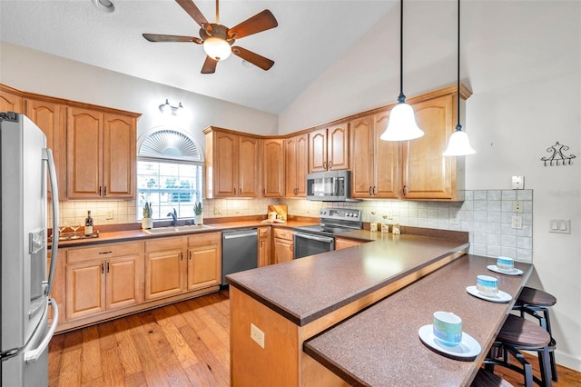 kitchen with pendant lighting, stainless steel appliances, decorative backsplash, sink, and kitchen peninsula