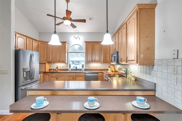 kitchen with decorative light fixtures, sink, a kitchen breakfast bar, and appliances with stainless steel finishes